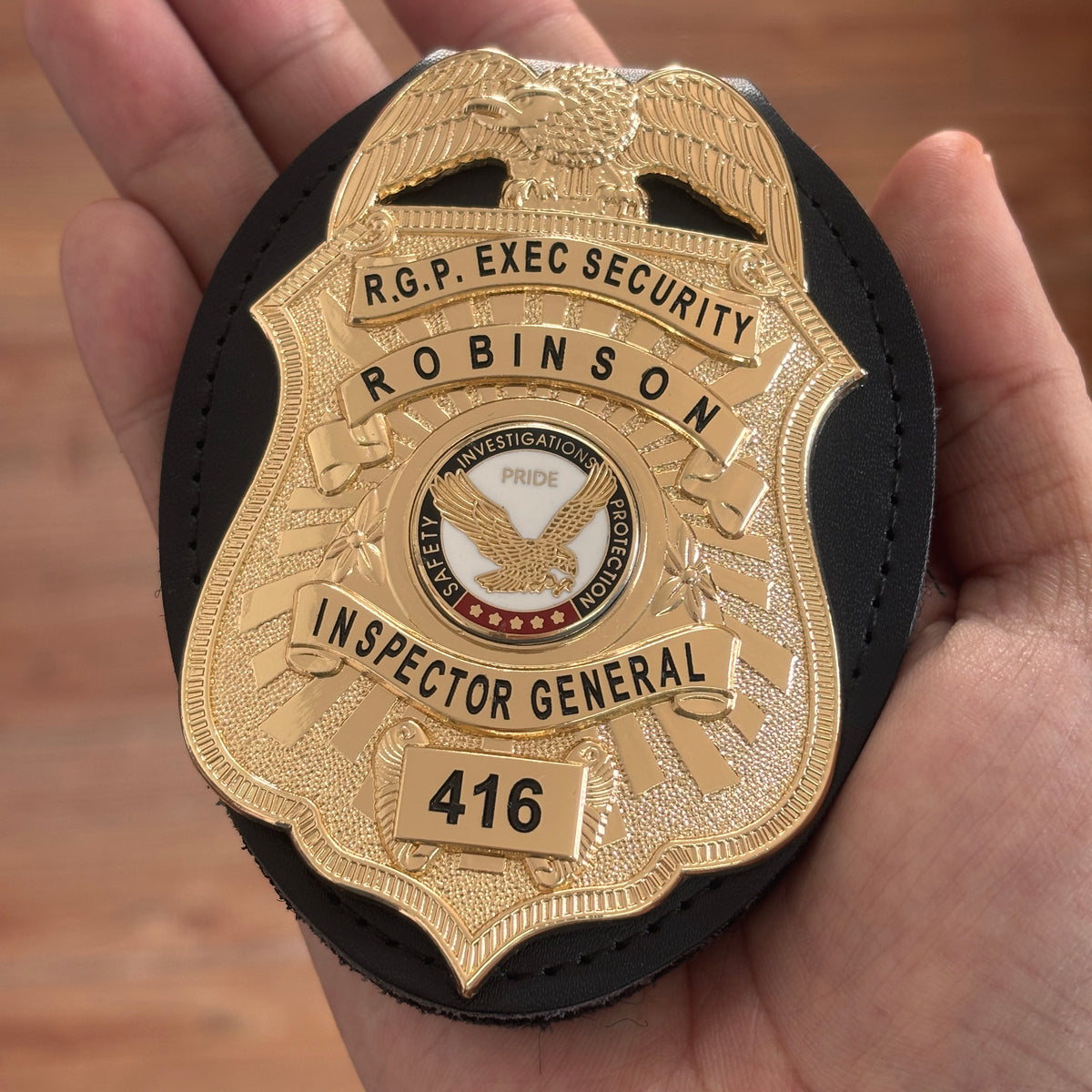 Gold-tone eagle-top executive security badge in a black holder, showing ROBINSON, INSPECTOR GENERAL, an eagle emblem, and number 416